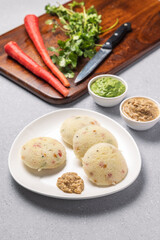 vegetable rawa idli served with coriander and coconut chutney with tomato sauce