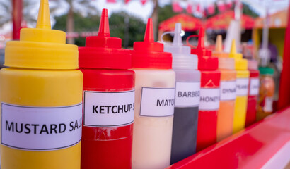 Multiple flavor sauce bottles in a food card at a food festival. Different sauces in plastic