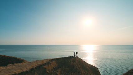 Fototapeta premium The hiker couple standing on a mountain against the beautiful sunset