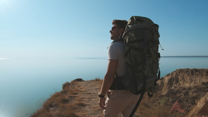 The man with a backpack standing on the sea background