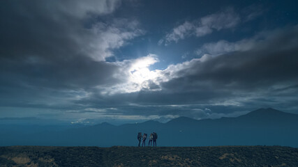 The group of hikers standing on night mountains background