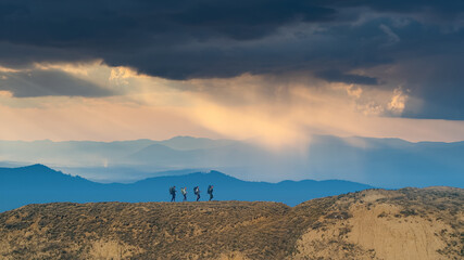 The four hikers walking on picturesque mountains background