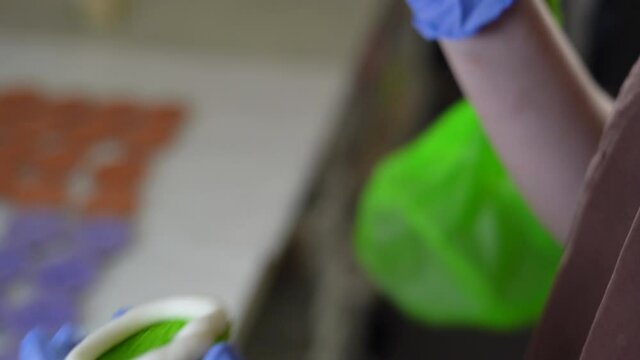 Filling French pasta with purple cream. closeup female hands in gloves