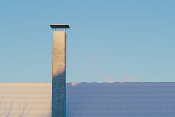 Snow covered roof and chimney against sky