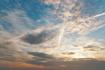 Morning blue orange sky, sun shining through clouds, some trails from airplanes visible