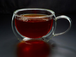 Glass cup with tea close up on dark background
