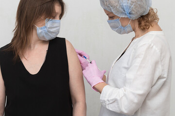 Covid-19 vaccination. A female patient receives a coronavirus vaccination. Intramuscular injection of the Covid vaccine during a doctor's appointment.