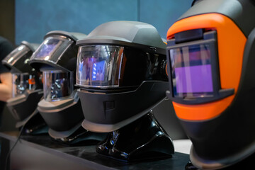 Row of protective welding mask helmets on table at exhibition, trade show - close up. Safety,...