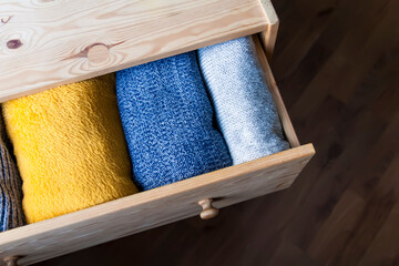 Open wooden dresser drawer with warm knitted woolen clothes. Home vertical storage. Wardrobe...