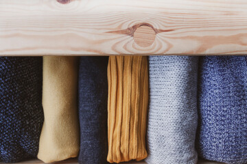 Open wooden dresser drawer with warm knitted woolen clothes. Home vertical storage. Wardrobe...