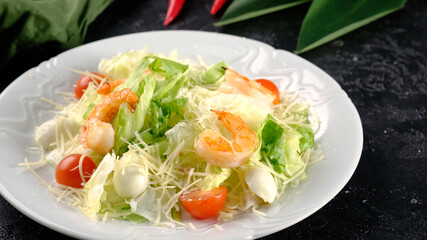 Caesar salad with shrimps on a dark background