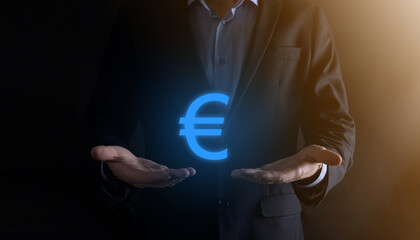 Businessman holds money coin icons EUR or Euro on dark tone background..Growing money concept for business investment and finance