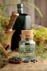 Juniper tincture and juniper berries on an old wooden table.
