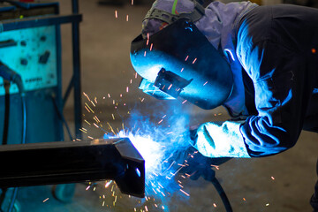 Welder is welding the steel in the factory.