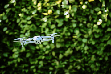 Drone departing in a garden with a hedge