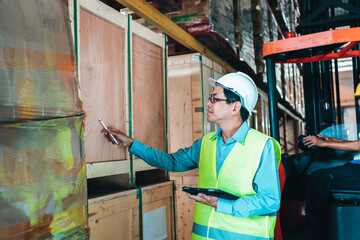 Working Team at warehouse. asian man Engineer use Tablet Information to further placement in storage department. background driver at Warehouse forklift loader works with goods