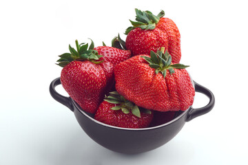 Bowl of ugly but fresh strawberries on white background