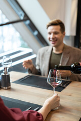 Hand of young woman sitting by served table in front of her happy boyfriend