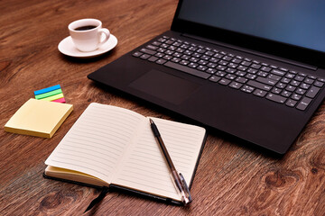 Laptop, notebook with a pen and coffee on the table closeup. Remote work. Distance learning. Online educetion, courses. 