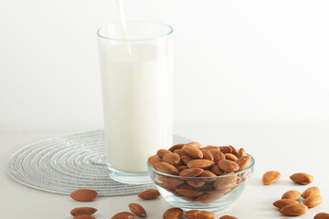 A glass with almond milk and the bowl with almonds