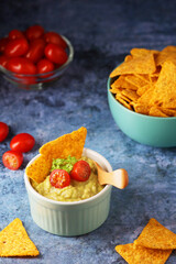 Homemade guacamole with corn chips and cherry tomatoes