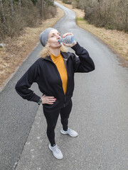 Adult caucasian woman in 40s exercising / jogging on a suburb road in winter / autumn season time.