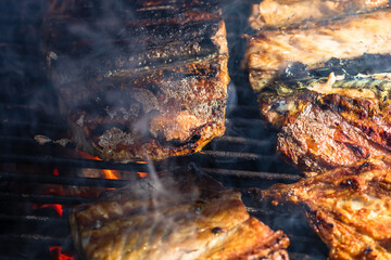 Grilled mackerel fish with smoke on a charcoal barbecue grill.