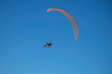 Man flying on a parachute in the blue sky