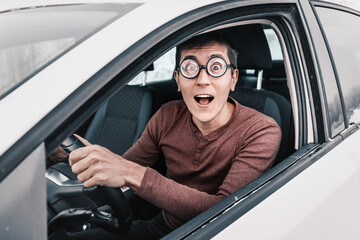 ridiculous geek driver is staring at the camera and holding the steering wheel. Concept of a novice...