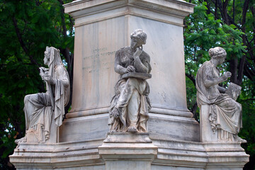 Marble statues on the base of the statue of Ioannis Varvakis in the garden of  Zappeion Palace of Athens, Greece.