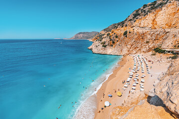 Fototapeta premium A chic beach with sun loungers and bathing vacationers. Top view of white sand and rich azure water