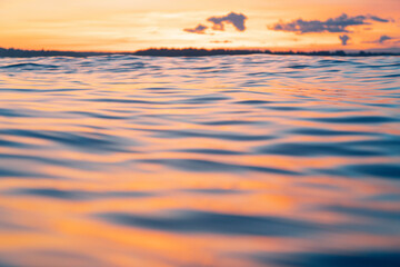 Water surface. View of a Sunset sky background. Dramatic gold sunset sky with evening sky clouds over the sea. View of a Crystal clear sea water texture. Landscape. Small waves. Water reflection