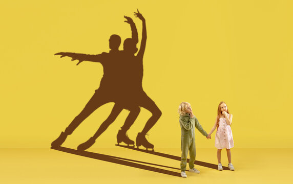 Childhood and dream about big and famous future. Conceptual image with boy and girl and drawned shadows of figure skating athletes on yellow background. Childhood, dreams, imagination, education