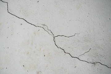 Concrete cement wall was cracked in the house where no people to live. Wall damage with crack. White cement construction material texture. Detail of ruin and destruction