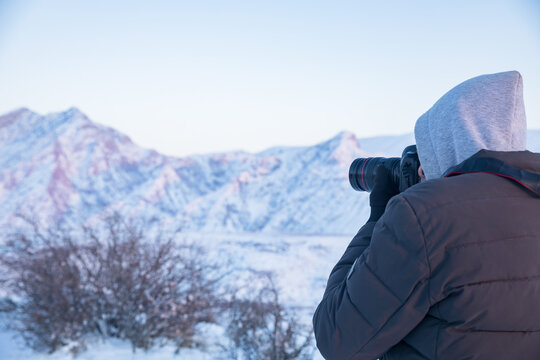 traveler with camera takes pictures of the snowy mountains