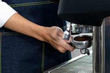 Closeup of Barista hand holding ground coffee for preparing espresso. Barista preparing portafilter before making cappuccino in a coffee shop.