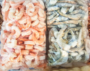 Two large plastic bags of frozen raw and cooked shrimp, on the counter of the fish market