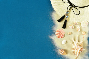 Sea collage with seashells, straw hat with a ribbon and sand on the turquoise background, top view.