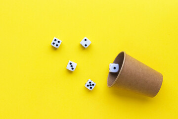 Gaming dice and cardboard cup on yellow background. Playing cube with numbers. Items for board...