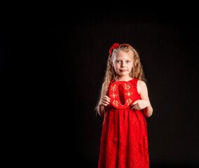 O holds a child holding in his hand the letter LOVE Valentine Valentine's background, , on the floor hearts a lovely layout. form a holiday. forever, joy in a red girl dress, barefoot