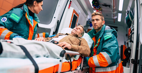 Serious and professional team of doctors in the ambulance moving on a patient into the hospital during an emergency situation. © My Ocean studio