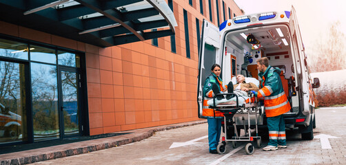 Serious and professional team of doctors in the ambulance moving on a patient into the hospital...