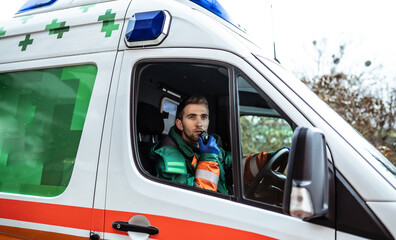 Professional and confident young man doctor looking on the camera with ambulance background © My Ocean studio