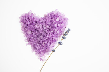 Heart-shaped lavender body salt on a white background with a branch of natural lavender. Body treatment, skin care concept. Flat lay.