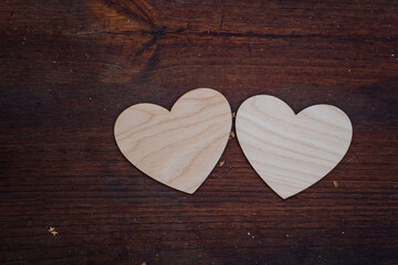 Two white wooden hearts lie on a brown wooden surface, valentine's day 