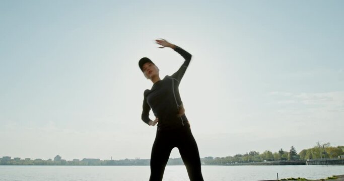 Young girl doing fitness on the beach doing exercises leaning to the side