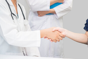 closeup hands of doctor patient shaking with trainee standing beside. white copy-space, healthcare medical care concept