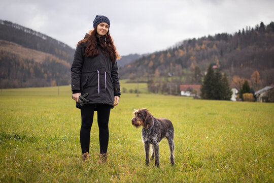 Fascinated face of a brown female Bohemian Wire-haired Pointing Griffon. Owner in winter clothes with a slight smile. The concept of the relationship between man and dog.