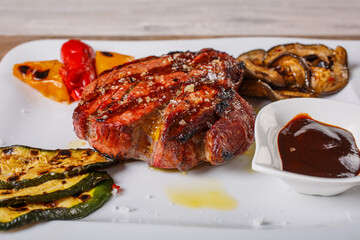 Filetto di manzo servito con salsa barbecue, zucchine grigliate, peperoni grigliate e melanzane grigliate