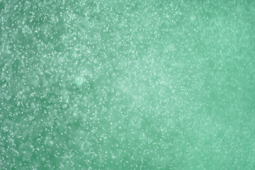 Abstract festive background with selective focus. Bright particles on green background. Splashes, space energy flow